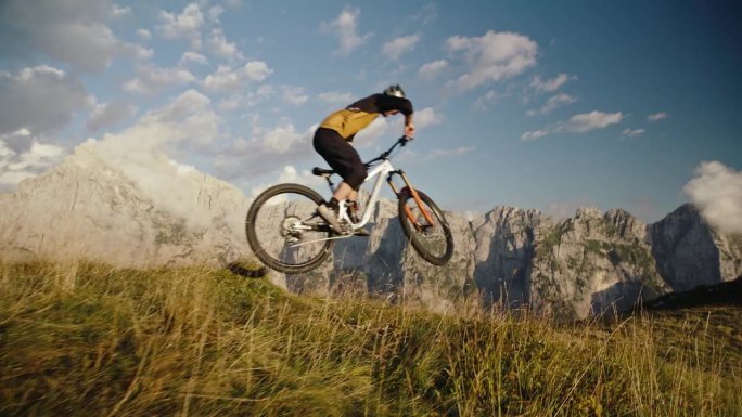 在阳光明媚的日子里，山地自行车手在草地上用自行车表演特技