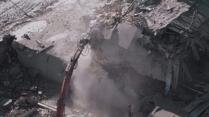无人机拍摄的被毁建筑物。拆除建筑物。挖掘机在拆迁现场清理垃圾。