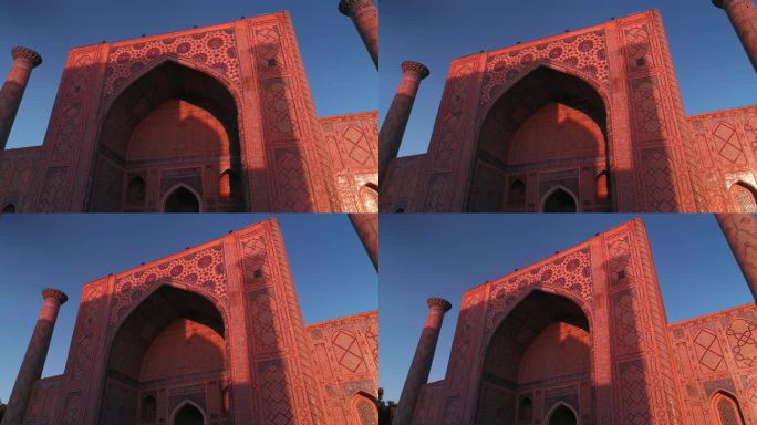 一架无人机在乌兹别克斯坦撒马尔罕的比比-康姆清真寺附近飞行。这座建筑被粉红色的晨光照亮了。万里无云的