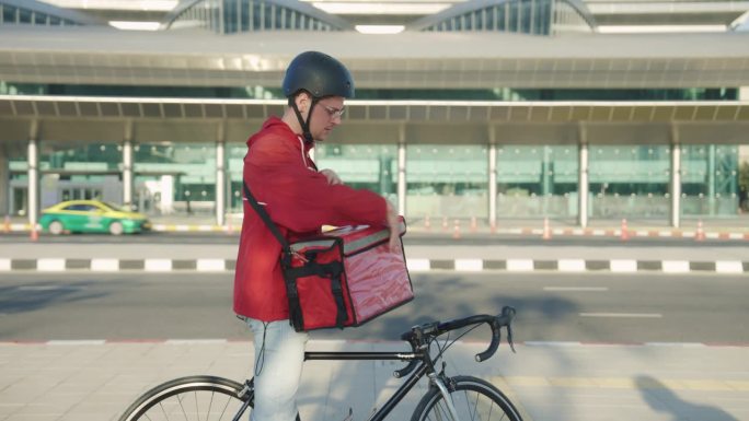骑自行车的人拿着电话取货单，把它放在背包里