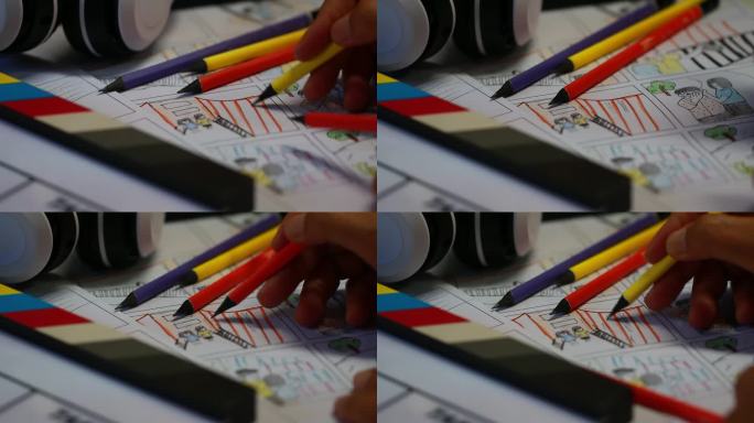 电影概念前期制作的故事板视频:设计师手持彩色铅笔画在素描板纸箱模板上，耳机在石板上，在工作室的背后过