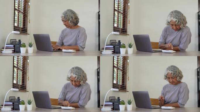 年长的女性在网上计算、写作、支付账单，在家工作时准备财务报告。专注于成熟女性，从事会计工作，忙于财务