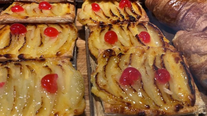 美味的水果挞与釉和牛角面包在木板上。