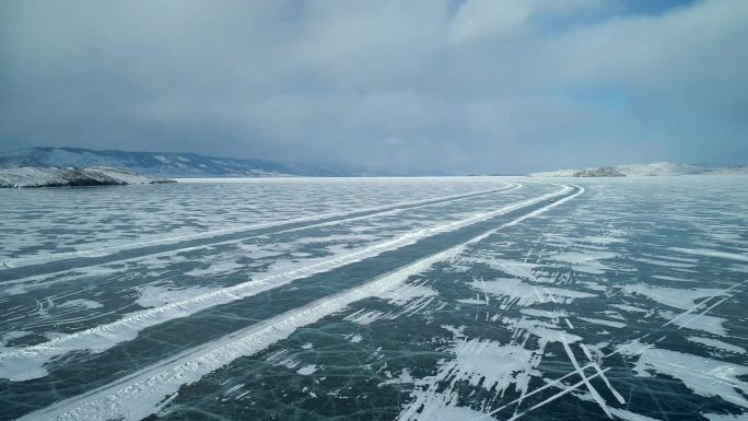 冬季贝加尔湖冰面上的鸟瞰图。结冰的道路上行驶着汽车。冬天的风景。飞越冰冻的贝加尔湖。