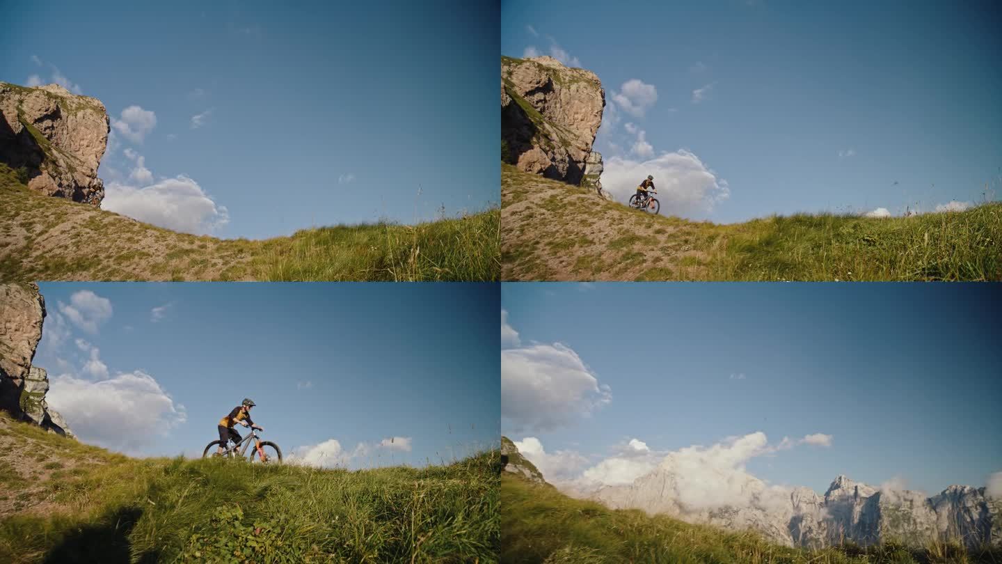 在落基山脉和蓝天的草地上，坚定的骑自行车的男子表演特技的手持镜头