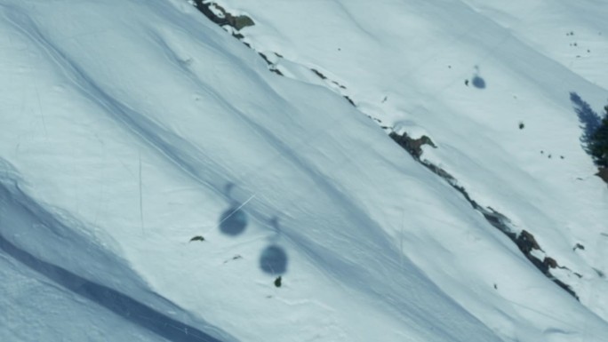 在滑雪季节，从覆盖着雪的山上的高处看到多个滑雪缆车运输的阴影-从乘客的角度来看