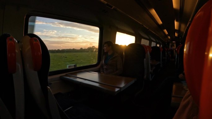 镜头光晕:一个美丽的早晨，一位女士坐在火车上穿越乡村