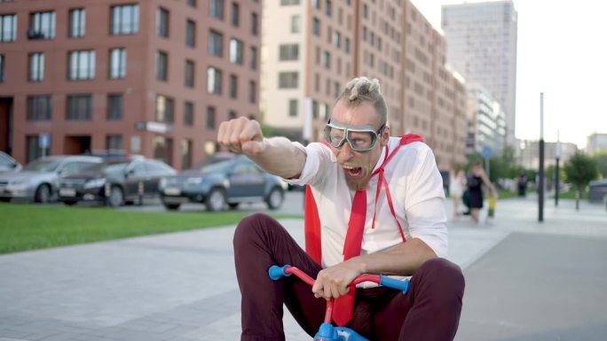 穿着西装的年轻商人在户外骑着自行车。领导者成功的赢家超级英雄疯狂的人与红斗篷骑自行车在城市街道，业务