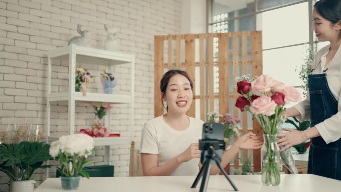 现代花店礼品店:两个亚洲有影响力的人在家工作，为现场销售和远程产品销售拍摄自拍视频。