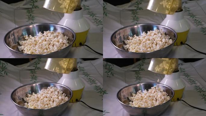用勺子搅拌爆米花(特写)，在铁碗里为晚上看电影准备爆米花