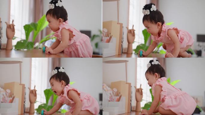 可爱的亚洲女婴，穿着漂亮的粉红色连衣裙，在家里客厅的高桌子上爬，试图够东西。
