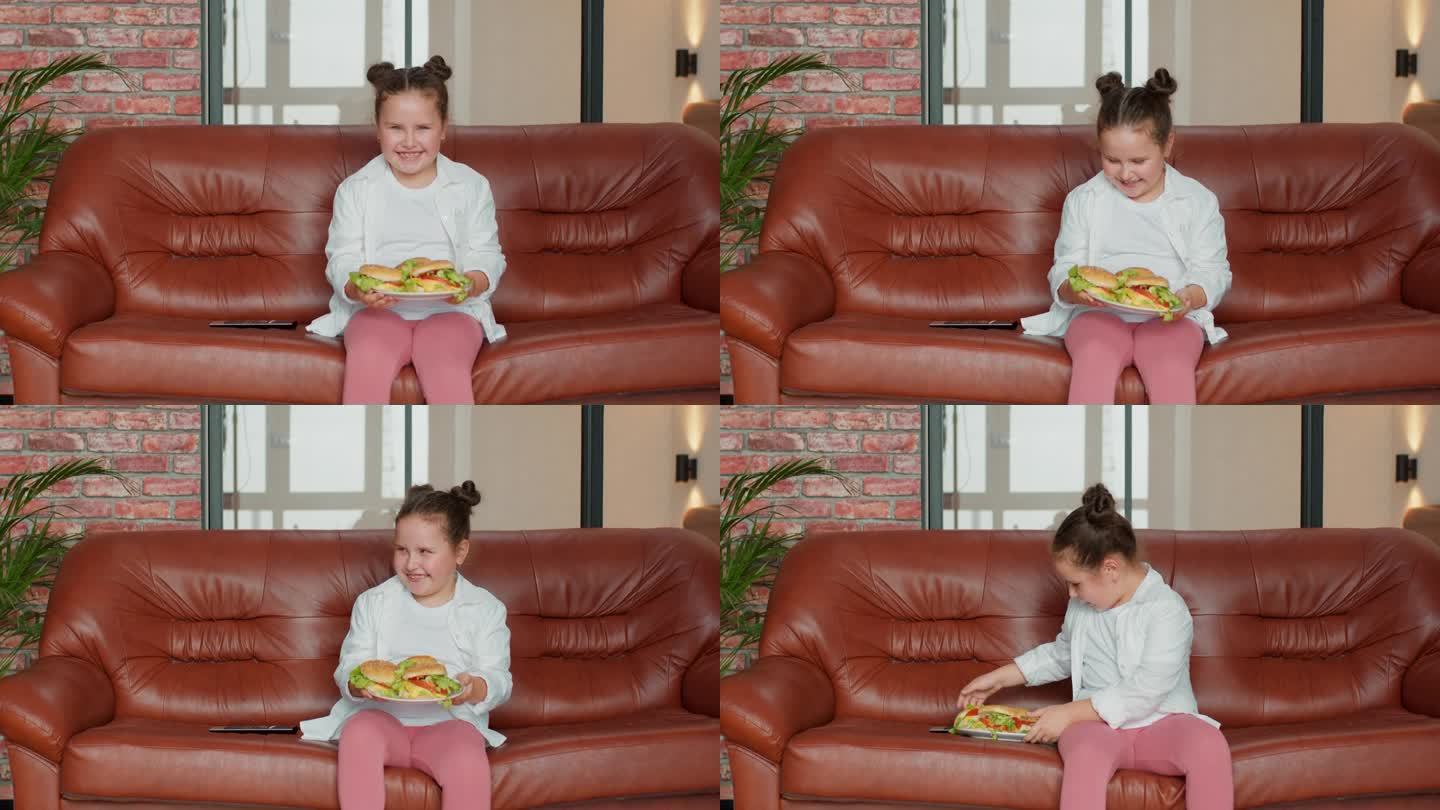 超重肥胖的快乐女孩坐在沙发上吃不健康的食物