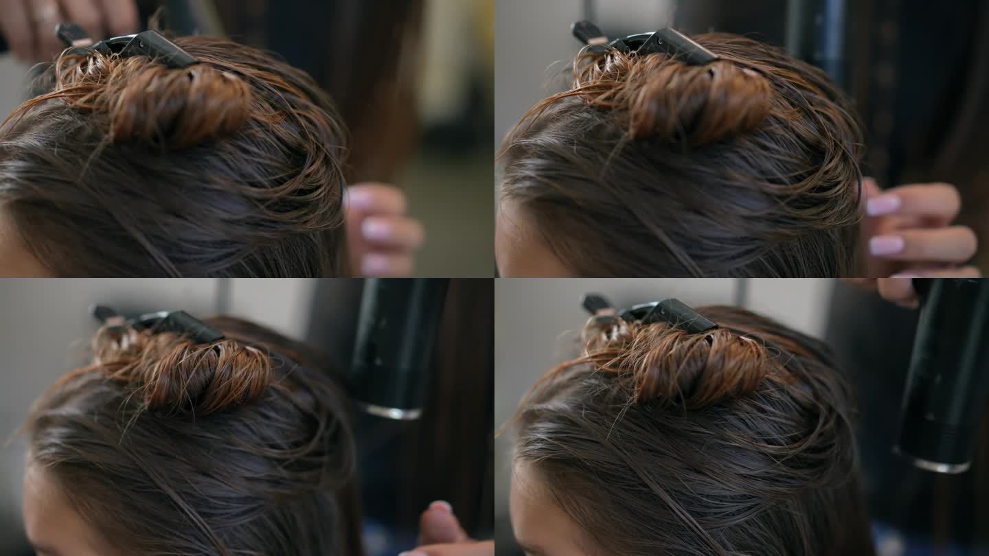 特写镜头。女发型师在发型师用吹风机吹干一个女孩的湿头发。