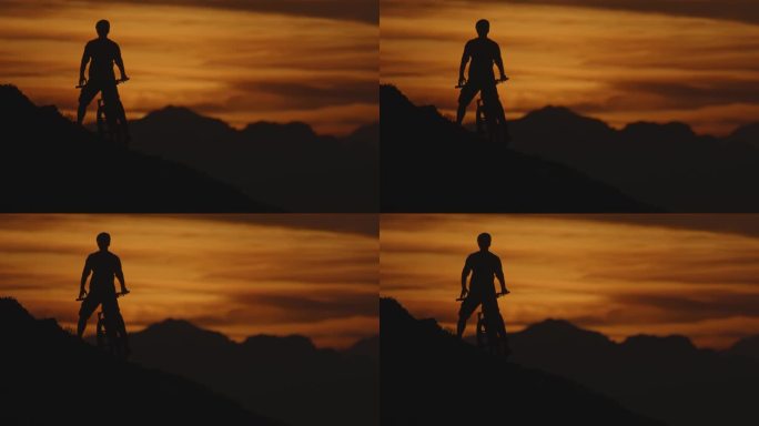 SLO MO剪影山地自行车站在山上对田园诗般的山脉和戏剧性的橙色天空自行车