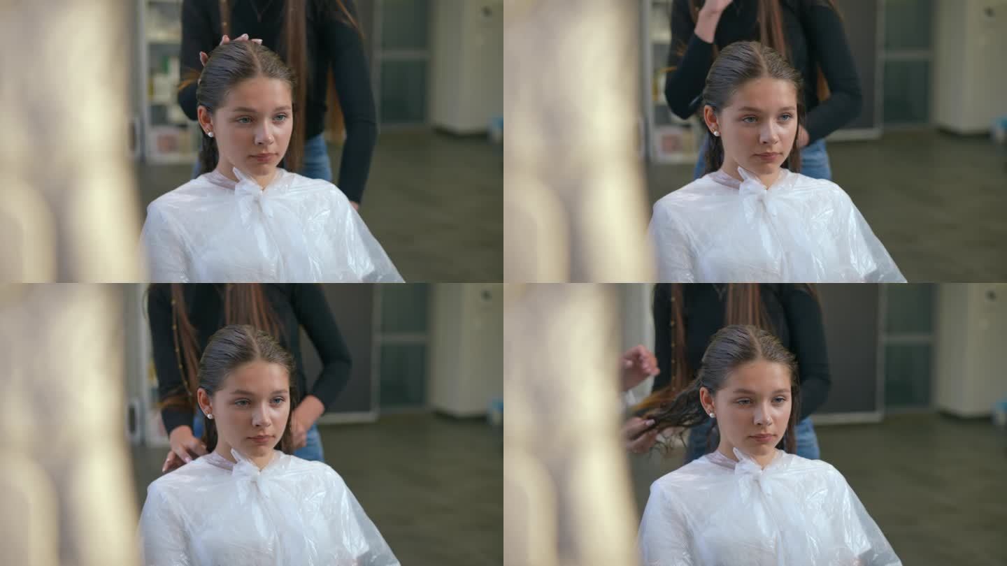 发廊里，女孩湿着头发坐在椅子上。美发师学习如何正确梳理湿发。通过镜子的反射来射击。