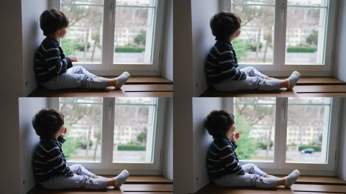 沉思的孩子坐在窗边向外看。沉思的小男孩从住处观察邻里