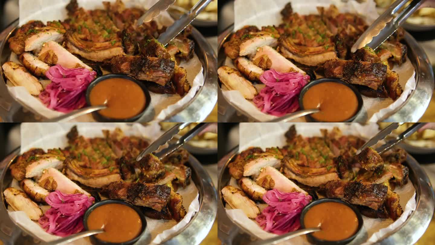 自助餐，客人把食物放在他们的盘子里不同类型的肉在肉盘上红番茄辣椒酱拿一块肋骨鸡牛肉和猪肉与甜菜色酸菜
