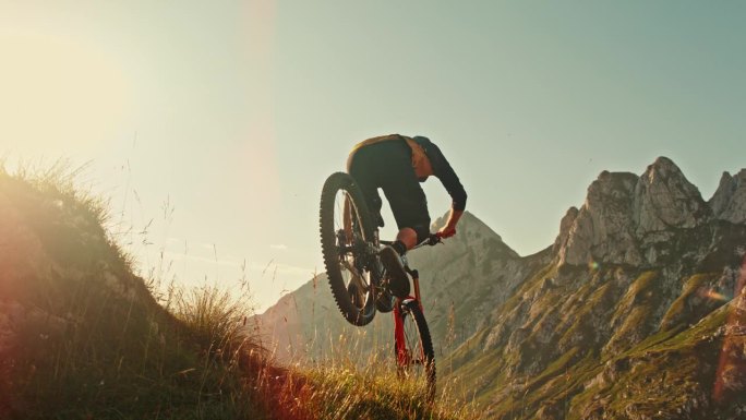 超级慢速MO时间扭曲效果确定男性骑手跳过草山对田园诗般的落基山脉在阳光明媚的一天