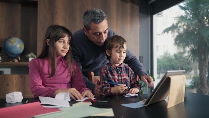 孩子和父亲做折纸玩具使用彩色纸按照步骤在视频教程中指示的数字平板电脑