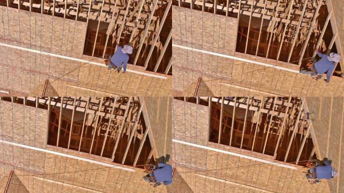 建筑行业的工人将钉子打入未来新住宅屋顶的胶合板中