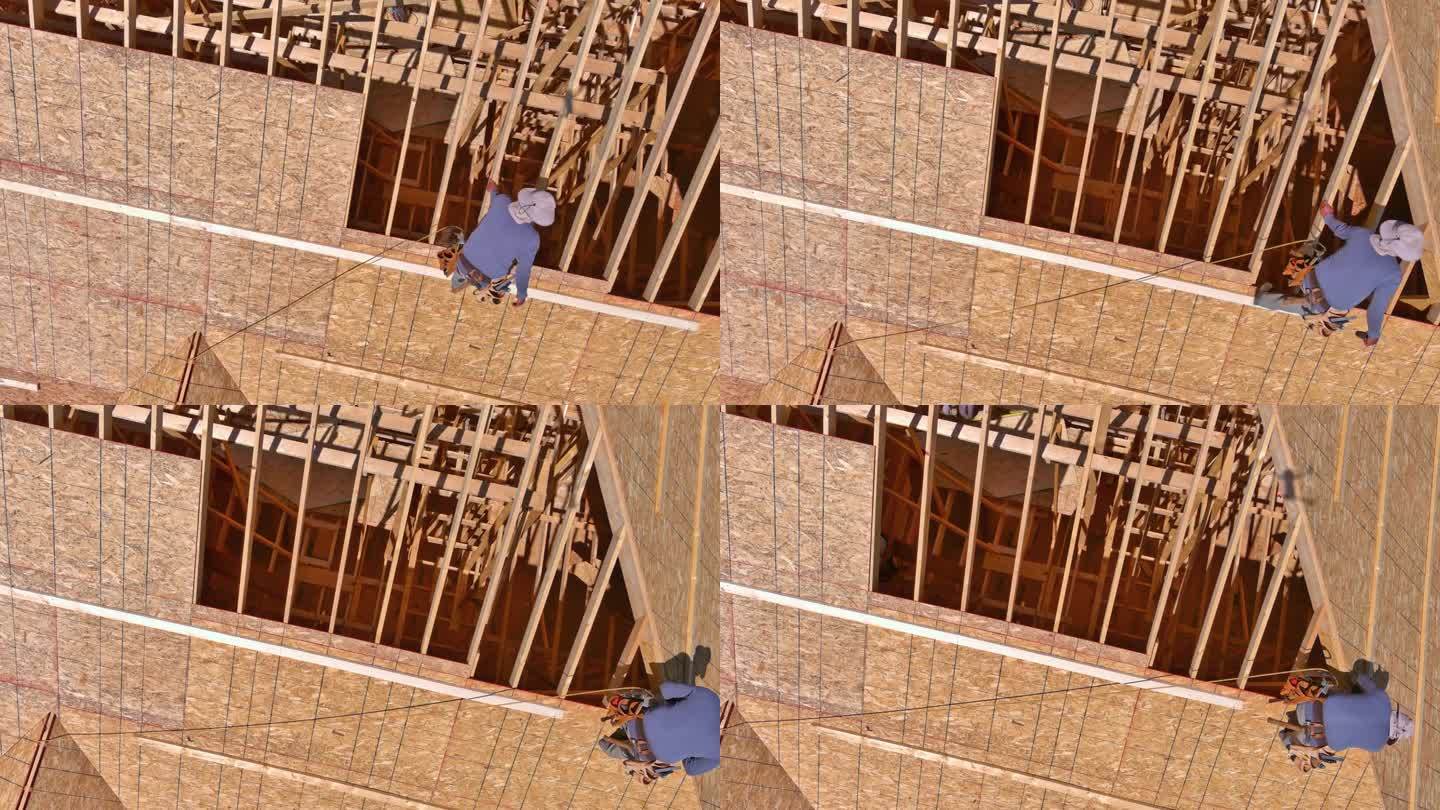 建筑行业的工人将钉子打入未来新住宅屋顶的胶合板中