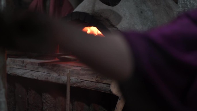面包艺术:烘焙师将新鲜出炉的面包从木质烤炉中铲出，在古老的石炉环境中