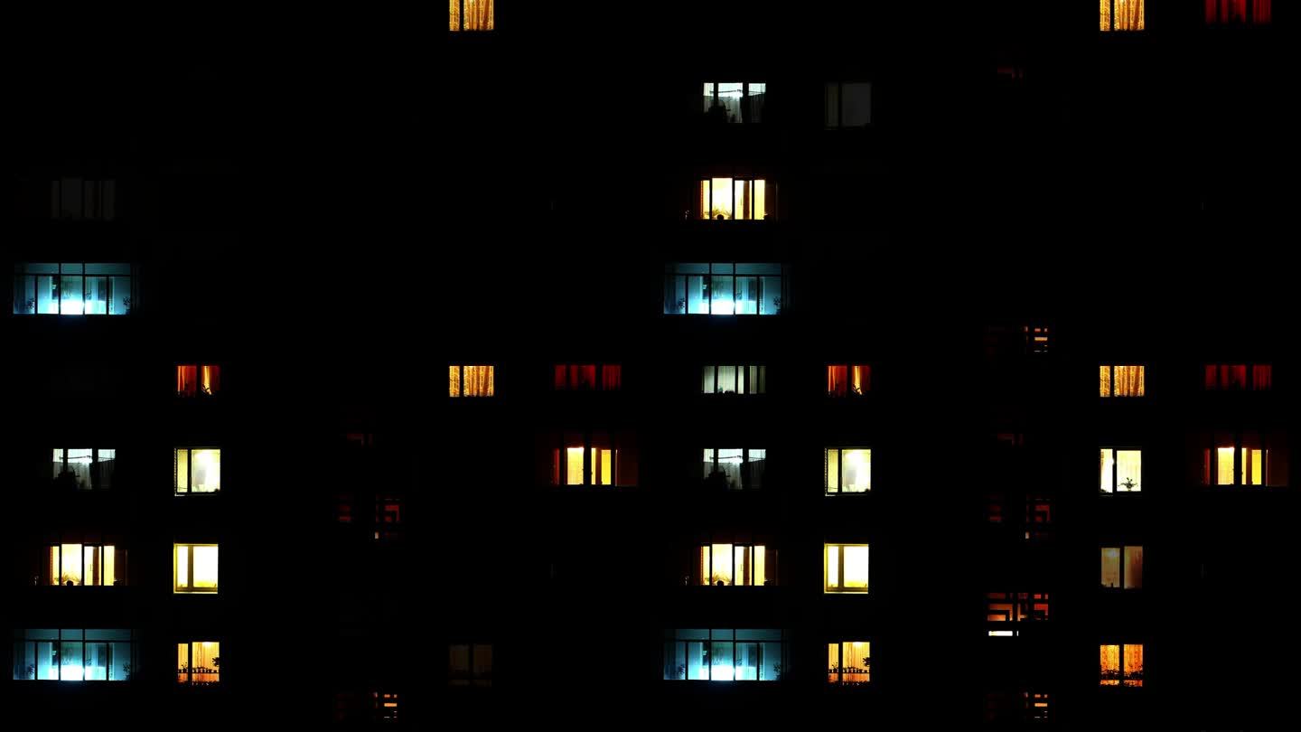 在漆黑的夜晚，打开有许多房间的房子的许多窗户的灯。大房子或建筑物的一组发光窗