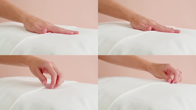 柔软的枕头特写。触摸白色靠垫在粉红色的背景。健康睡眠概念。