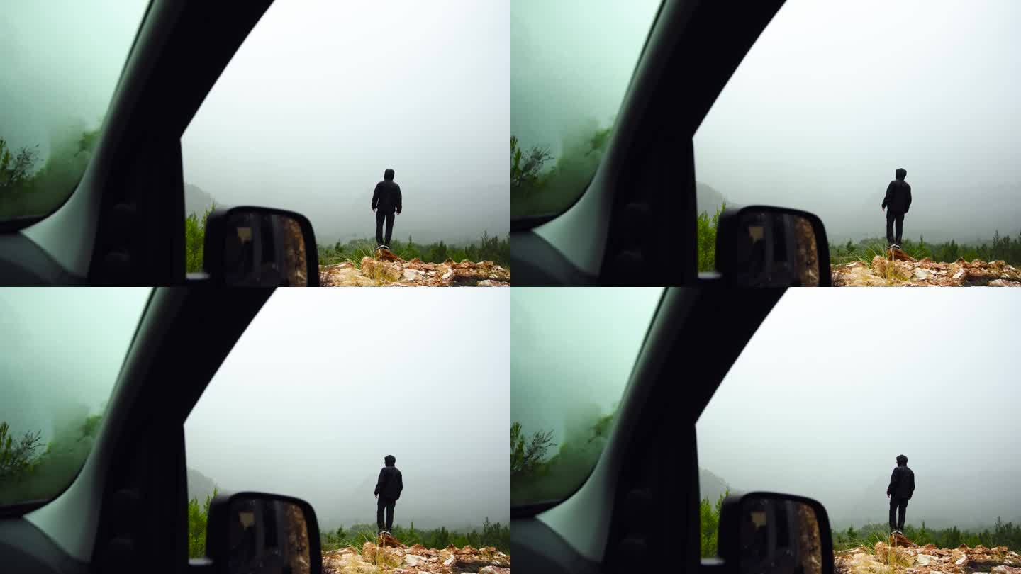 透过车窗看到的那个孤独的男人凝视着前方雾蒙蒙的景色。