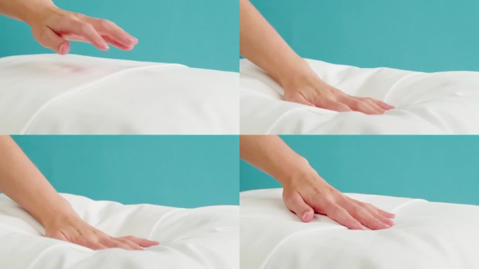 柔软的枕头特写。触摸白色靠垫在蓝色的背景。健康睡眠概念。