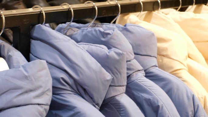 商店里挂着蓝白相间的冬季羽绒服，特写，侧视图。