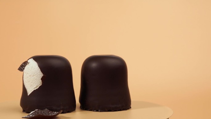 巧克力色的棉花糖在橙色的背景上旋转。