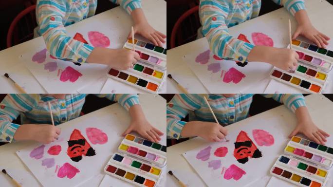 蹒跚学步的小女孩用水彩画，爱心贺卡。可爱幸福的家庭。孩子的艺术。工艺品，手工制作的概念。