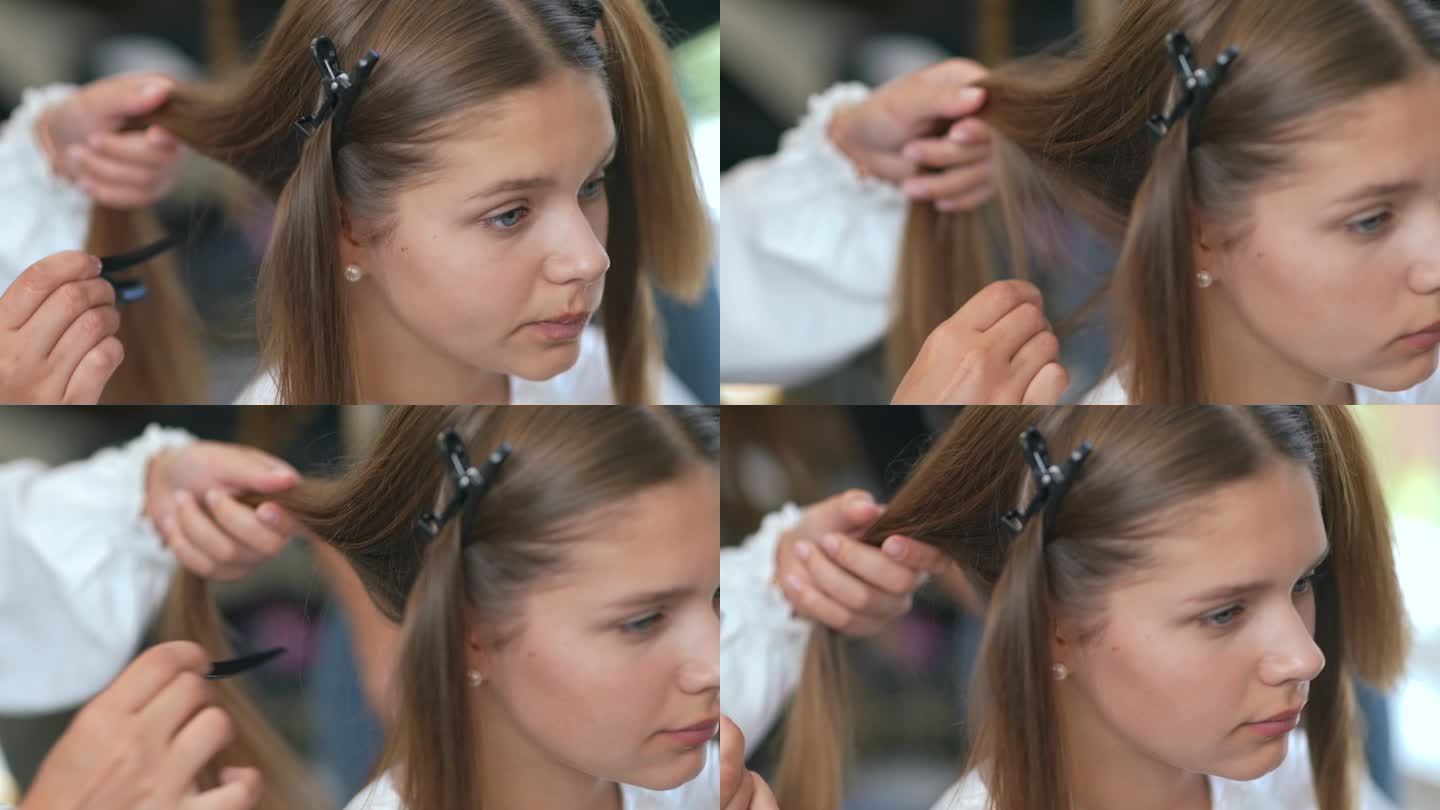 美发师的手的特写，他们把女孩头上的头发分开并用发夹固定。