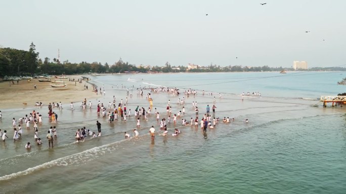 鸟瞰图:身着制服的孩子们在日落时在海边玩耍，快乐的年轻学生享受海浪，与不同的孩子们在海边休闲，日落沙