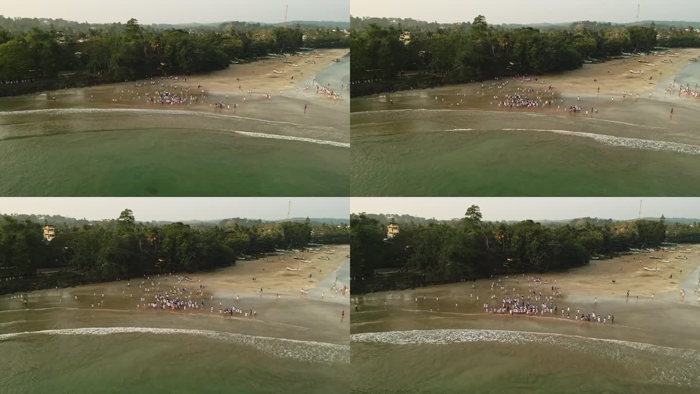 鸟瞰图:身着白色制服的孩子们在日落时在海边玩耍，孩子们享受海滩活动，年轻人聚集海岸线，学校夏令营的乐