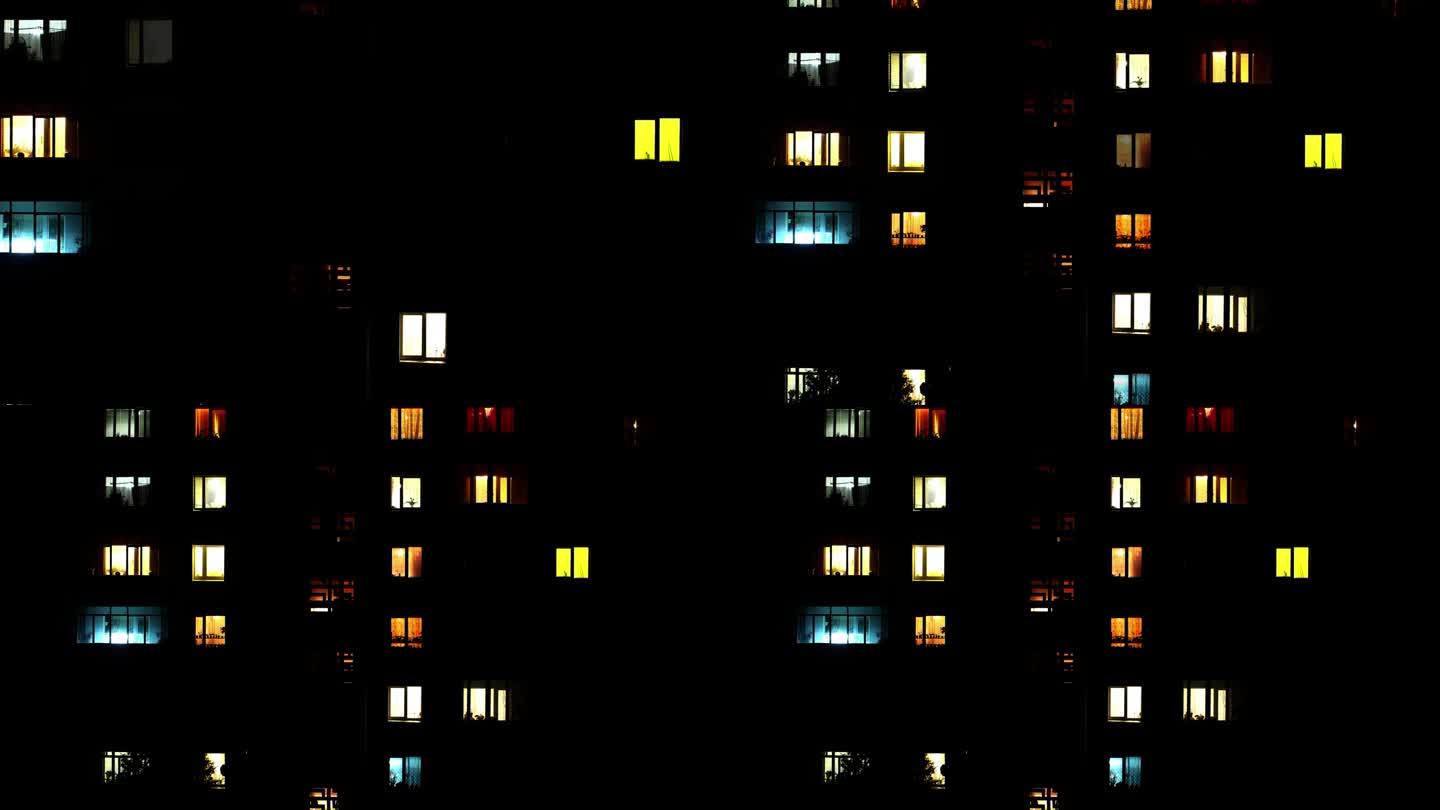 在漆黑的夜晚，打开有许多房间的房子的许多窗户的灯。大房子或建筑物的一组发光窗