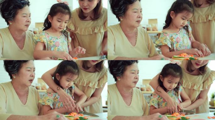 亚洲中年母亲和老祖母教他们的小女儿用刀切新鲜的胡萝卜和火腿，为家里的早餐准备一个健康的三明治。三代同