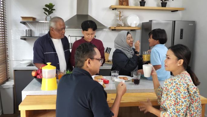 印尼多代家庭在家里吃早餐，孩子玩数码平板电脑