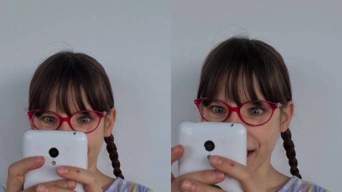 十几岁的女孩戴着眼镜，使用手机，手里拿着智能手机，垂直地看着屏幕