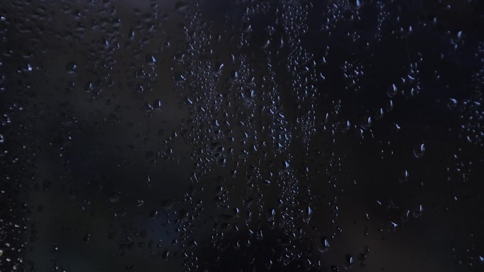 雾蒙蒙的玻璃带着水汽、雾气、流动。窗户上有水滴深色背景上的雨滴