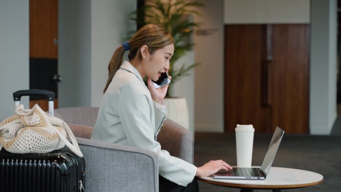 亚洲商务人士带着旅行行李，用手提电脑与客户在机场休息室、酒店大堂或办公楼进行商务虚拟会议