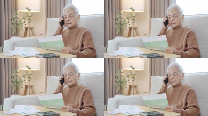 快乐的亚洲老年妇女，老年人坐在沙发上拿着各种费用账单网上购物用智能手机在线支付