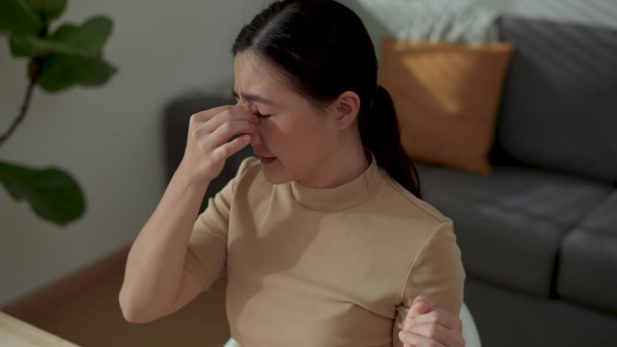 亚洲女性在家办公时眼睛酸痛。