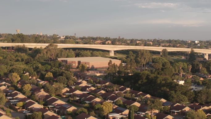 南非百夫长高速列车桥梁和房屋的缓慢旋转无人机镜头