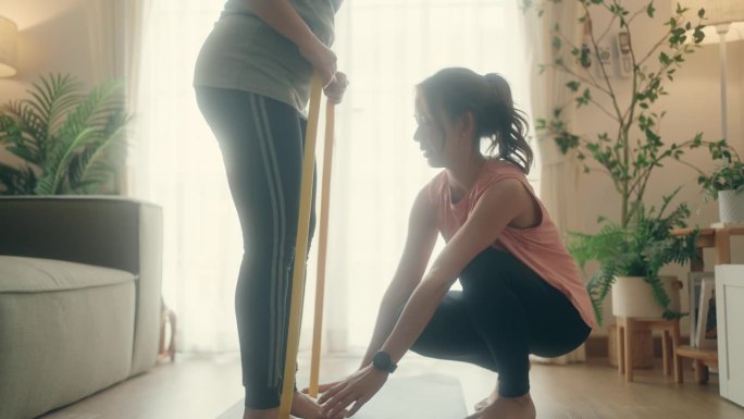 授权家庭锻炼:亚洲私人教练指导年轻女性和成熟女性在健身会议。