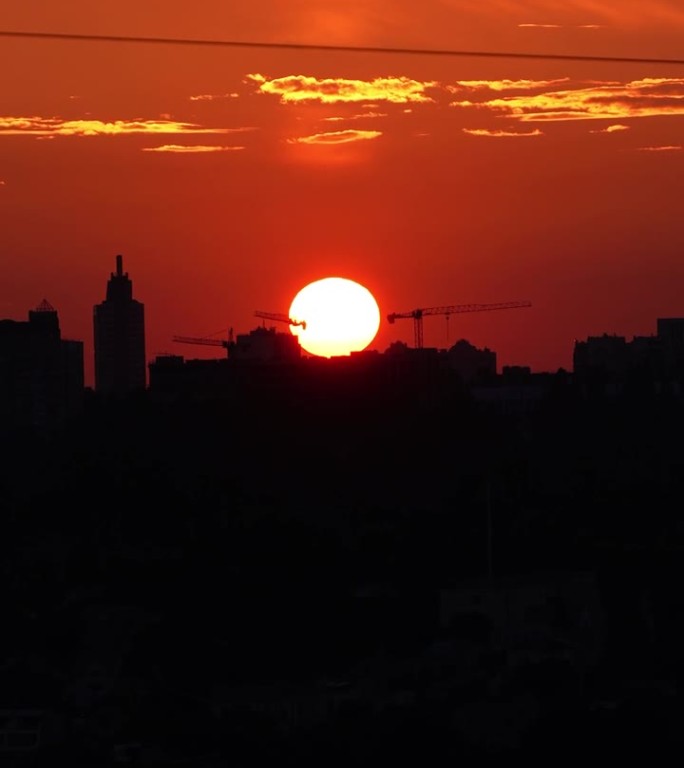 夕阳在大城市的背景下。夕阳与橘红色的天空在城市景观与建筑物的剪影