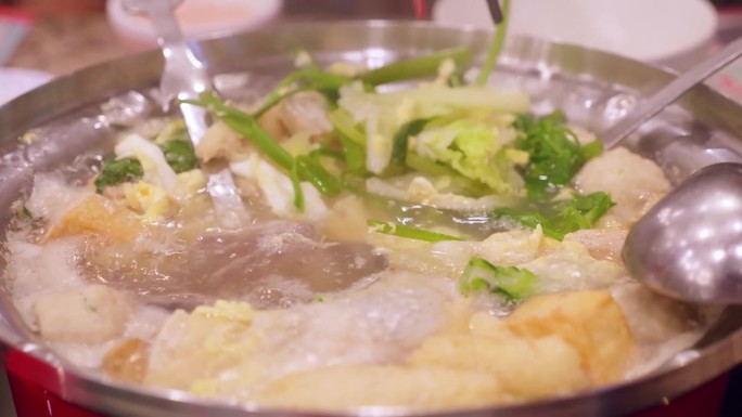 筷子从沸腾的寿喜烧锅中取出蔬菜的细节