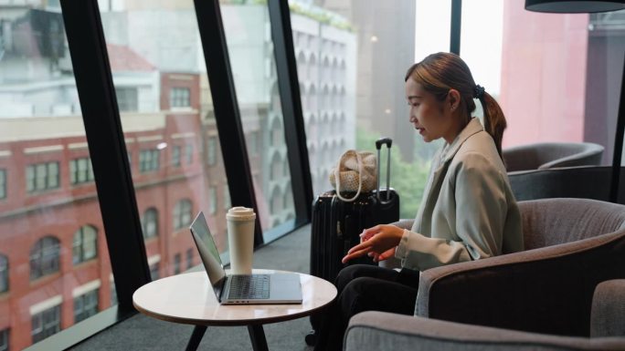亚洲女商人在机场候机大厅用笔记本电脑进行视频通话虚拟会议。实时在线沟通和业务咨询预约