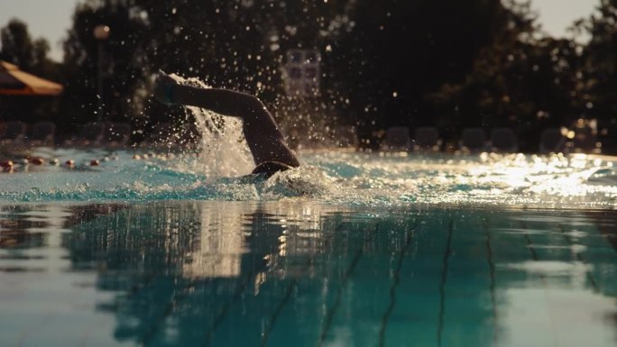 慢动作充满激情的男子游泳运动员在度假村的游泳池自由泳